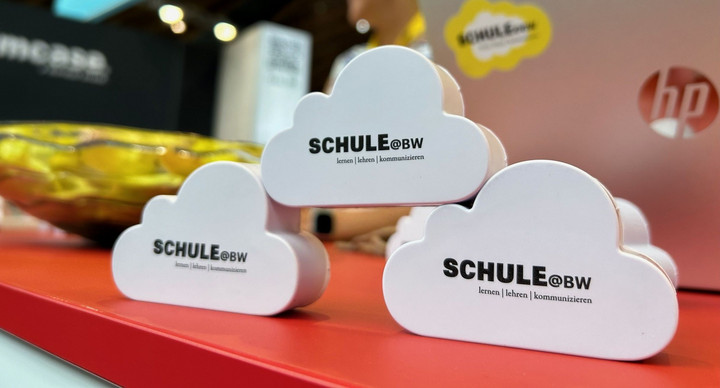 Das Bild zeigt den Messestand in Nahaufnahme. Im Vordergrund sind drei aufgetürmte weiße Wölkchen mit der Aufschrift &amp;amp;amp;amp;amp;quot;Schule@BW lernen, lehren, kommunizieren&amp;amp;amp;amp;amp;quot; zu sehen.