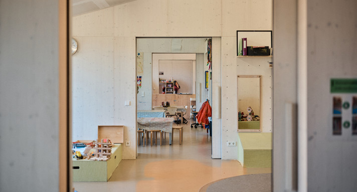 Ein leerer Flur, durch den man auf ein Zinmer mit Kinderspielzeug blickt. 