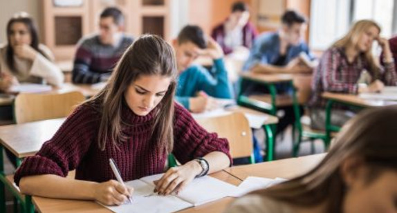 Female high school student writing a test in the classroom.