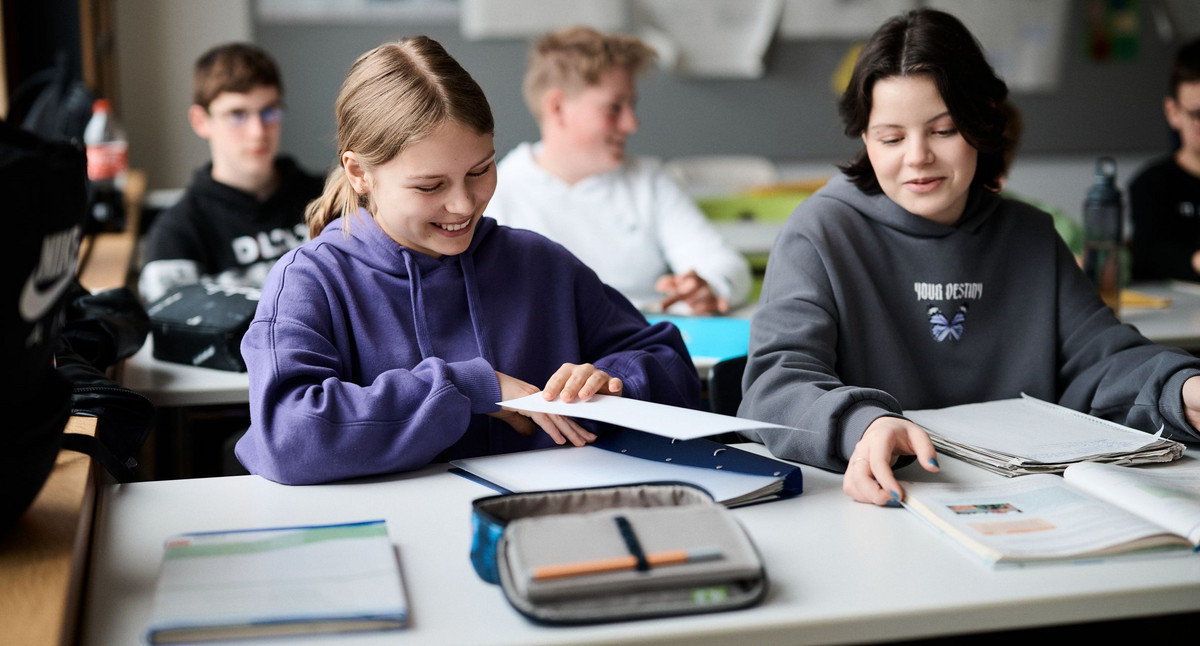 Zwei Mädchen sitzen im Klassenzimmer und unterhalten sich