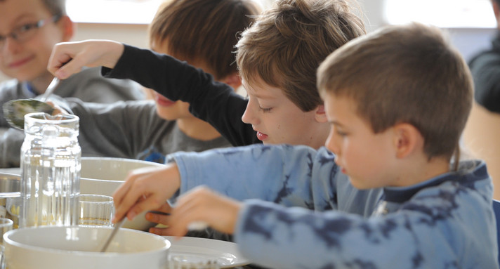 Mehrere nebeneinander sitzende Jungs essen Mittag in der Ganztagsschule
