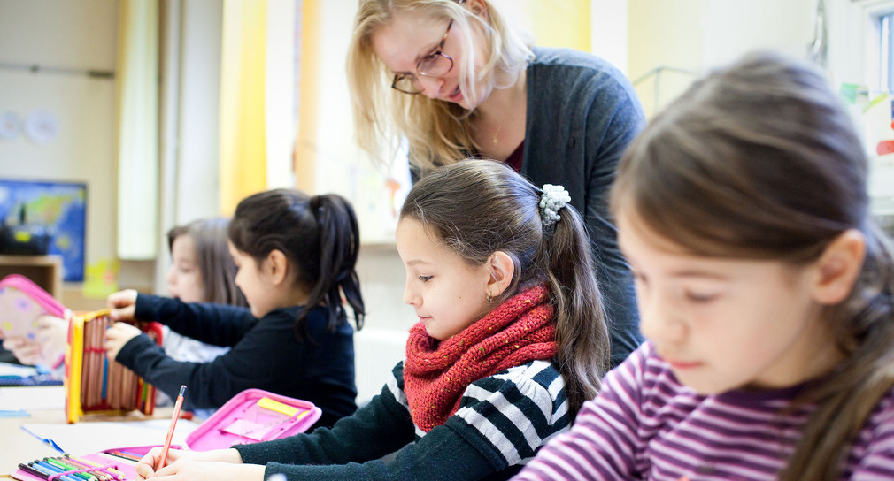 Eine Lehrerin in der Grundschule mit Schülerinnen und Schülern.