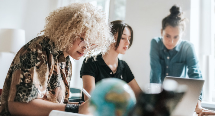 Multiethnische Gruppe von drei jungen Frauen, die gemeinsam an Konzepten für ein Projekt arbeiten