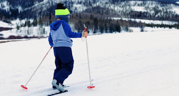 Sport Inklusiver Skilanglauf-Aktionstag Ein Kind von hinten auf Langlaufskiern im Schnee