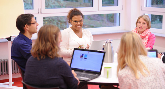 Lehrkräfte mit Laptops sitzen gemeinsam an einem Tisch