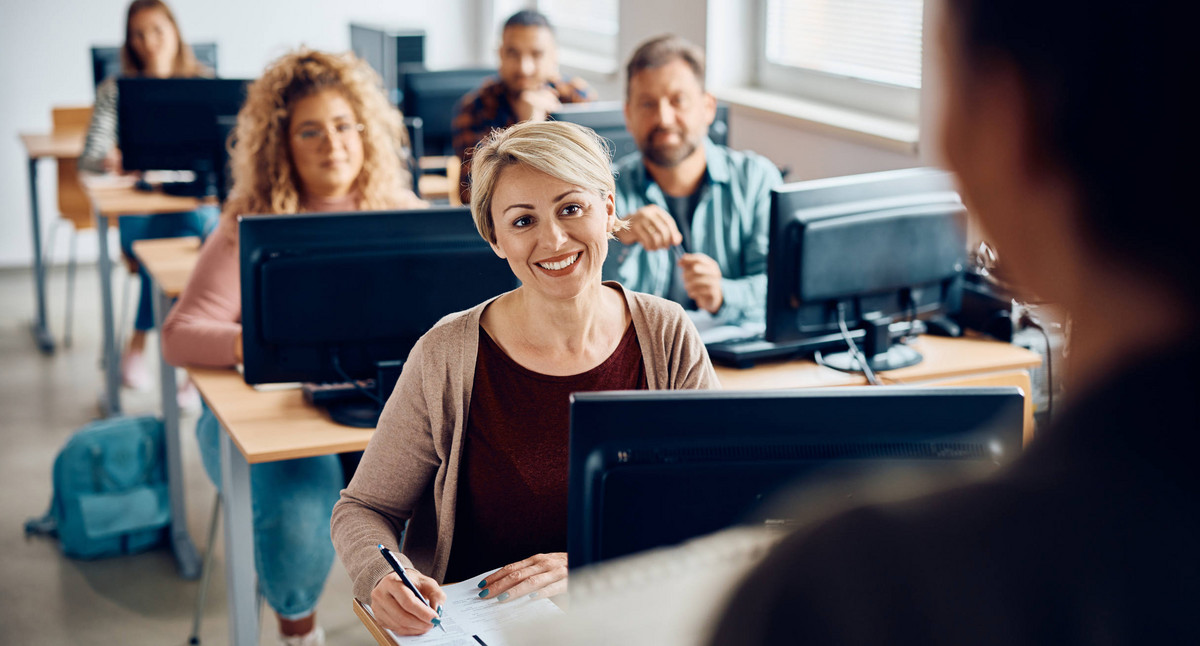 Männer und Frauen an PC-Arbeitsplätzen in einem Seminarraum