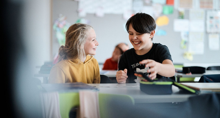 Eine Schülerin und ein Schüler unterhalten sich im Klassenzimmer