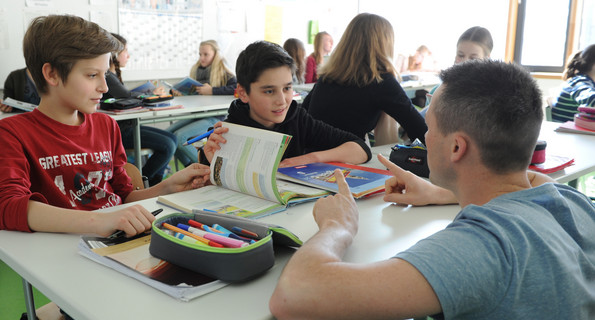 Schüler der Orientierungsstufe und ein Lehrer hockt vor ihnen