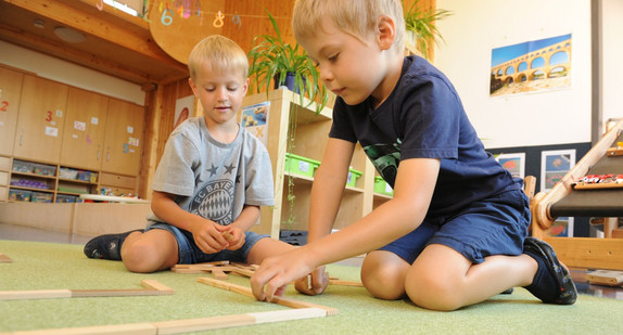 Zwei Jungen spielen auf dem Boden. 