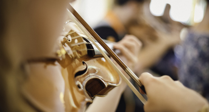 Gespielte Violine in Großansicht. Vom Musikanten sieht man nur die Hand