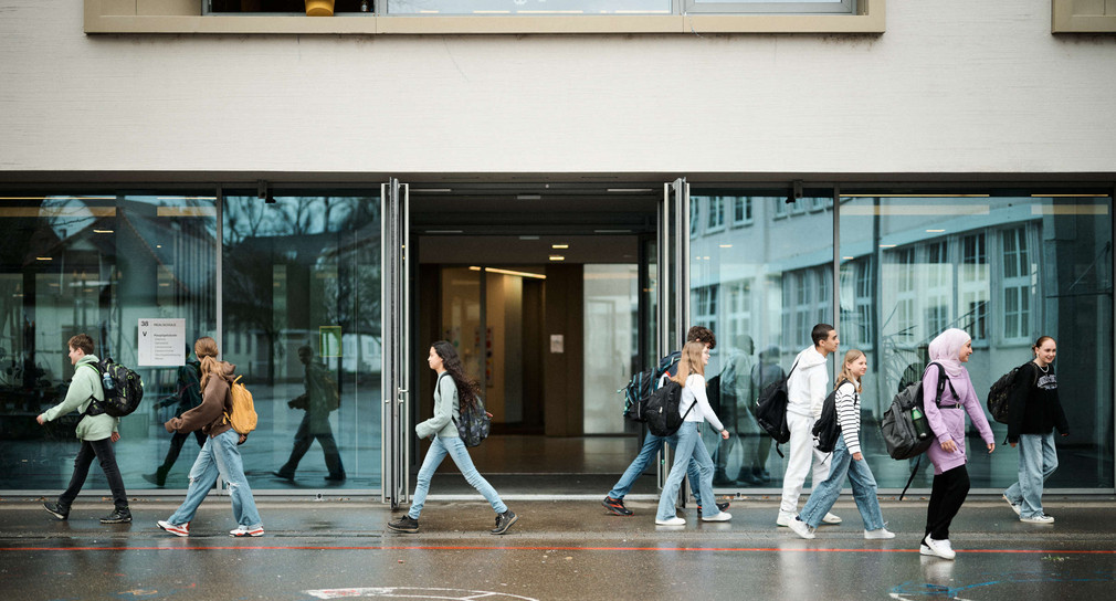 Schülerinnen und Schüler vor dem Eingang eines Schulgebäudes