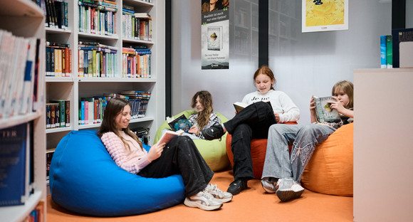 Vier Schülerinnen und Schüler sitzen in Sitzsäcken und lesen.