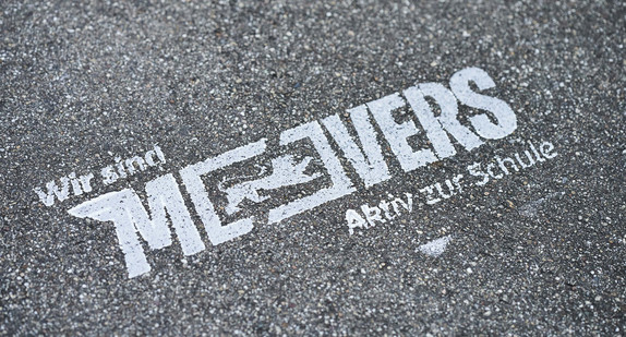 Auf grauem Asphalt steht in weißer Schrift "Movers".
