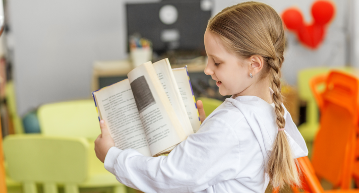 Ein Mädchen hält ein Buch in die Kamera.
