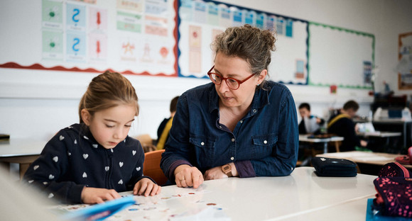 Eine Schülerin und eine Lehrerin nebeneinander an einem Tisch