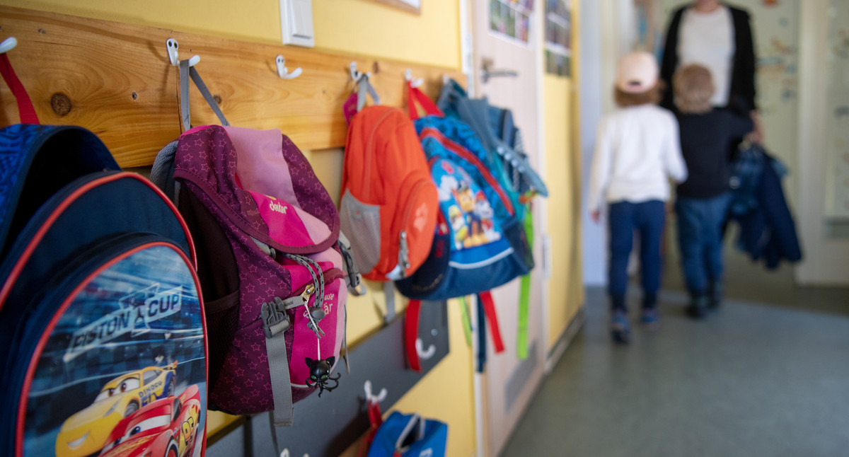 In einer Flur hängen an einer Wand viele bunte Kinderjacken. 