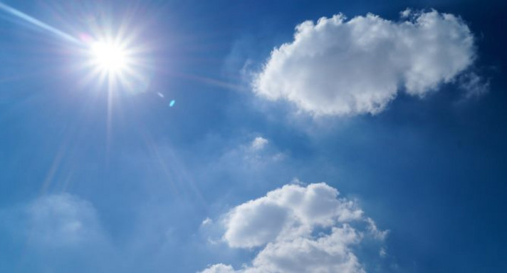 Ein blauer Himmel mit weißen Wolken und der Sonne.