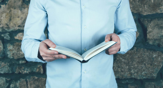 Ein Mann hält ein aufgeschlagenes Buch.