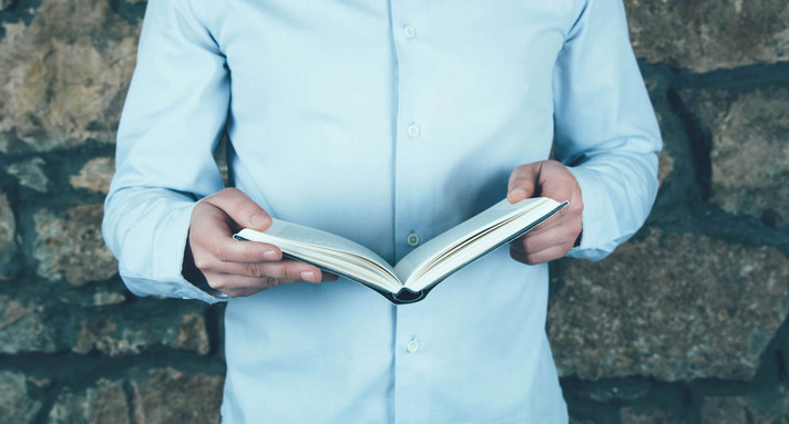 Ein Mann hält ein aufgeschlagenes Buch.