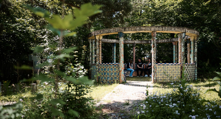 Drei Schüler sitzen in einem Rondell im Garten.