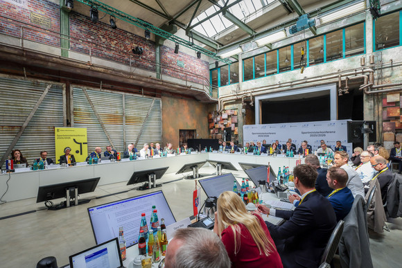 Sportministerkonferenz Sportministerkonferenz 8. und 9. Mai 2025 in Chemnitz Mehrere Personen sitzen an langen Tischen in einer Halle.