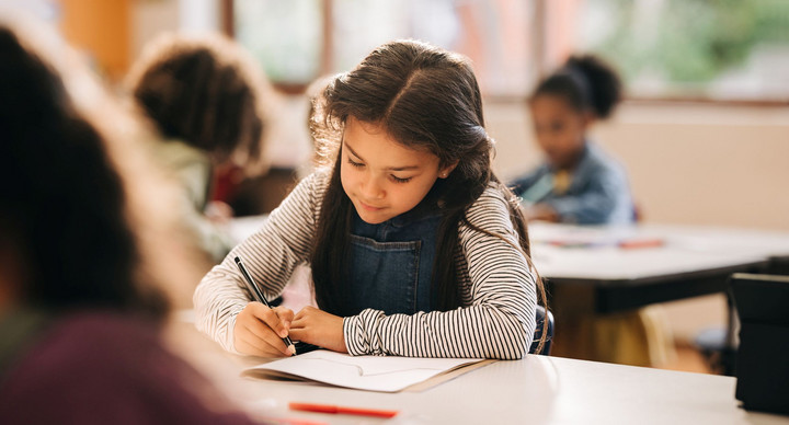 Kid writes on a book in a primary school class