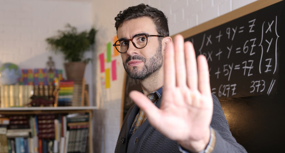 Male teacher showing stop sign with hand gesture
