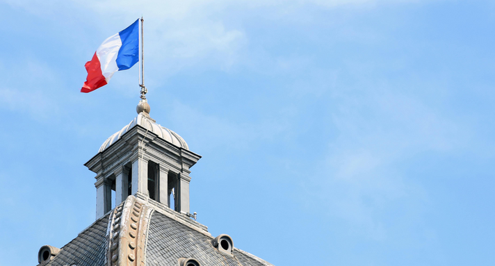 Eine französische Flagge weht vor blauem Himmel. 