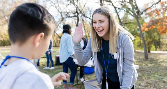 Community outreach volunteer coordinator greets young volunteer