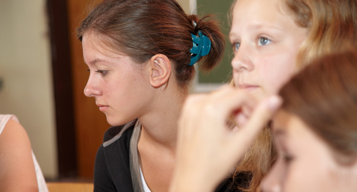 Mehrere jugendliche Schülerinnen, nebeneinander sitzend