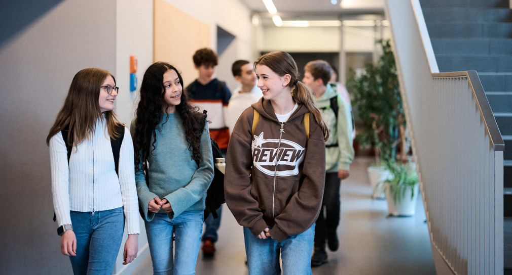 Schülerinnen und Schüler laufen durch den Flur eines Schulgebäudes