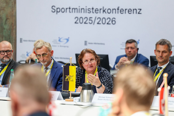 Sportministerkonferenz Sportministerkonferenz 8. und 9. Mai 2025 in Chemnitz Mehrere Personen sitzen an langen Tischen in einer Halle.