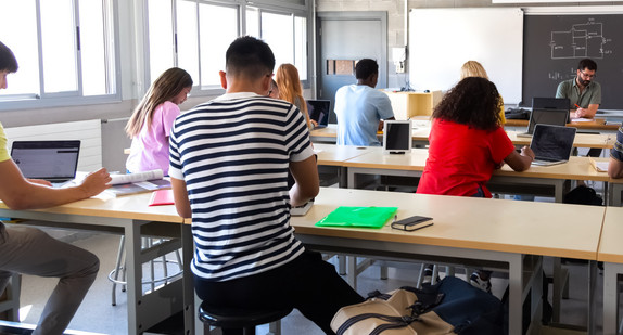 Schulklasse mit erwachsenen Schülerinnen und Schüler von hinten während des Mathematikunterrichts aufgenommen