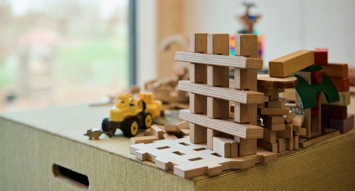 Auf einem Tisch liegen Holzbauklötze und ein gelber Bagger.