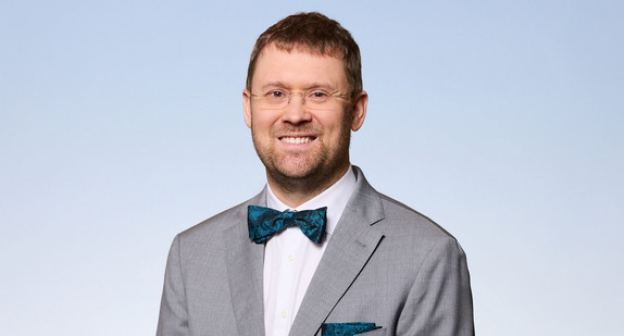 Mann in Anzug vor blauem Hintergrund