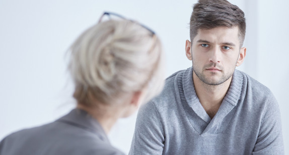 Beratungsgespräch, geführt von einer Frau von hinten aufgenommen mit einem vor ihr sitzenden jungen Mann