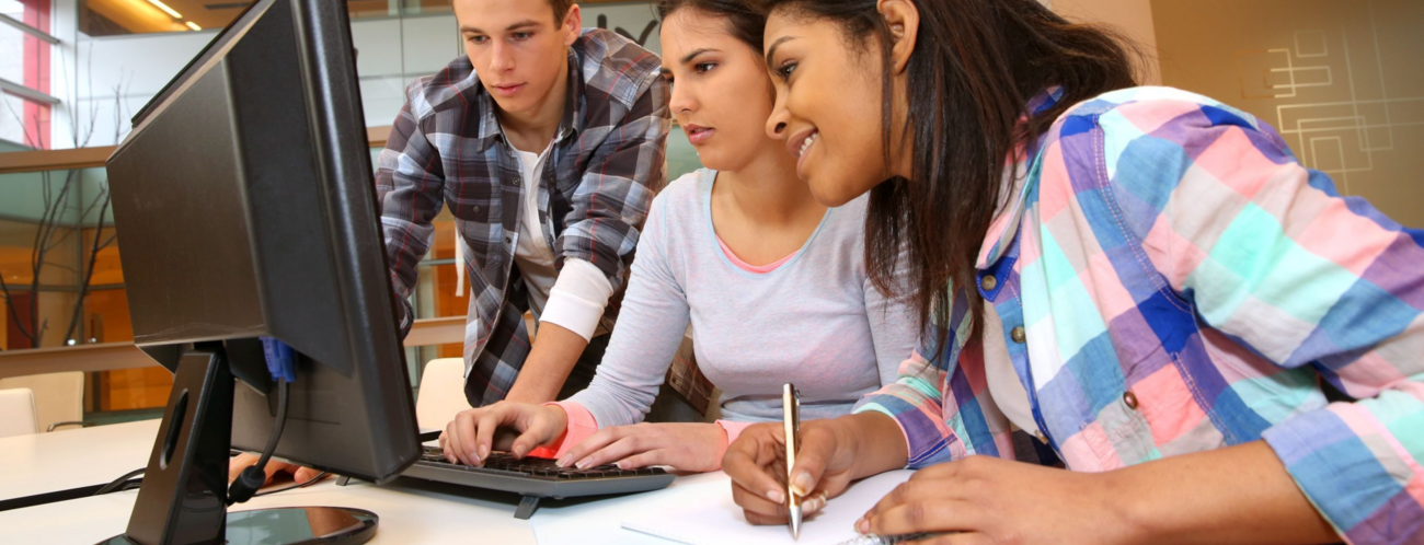 Jugendliche Schülerinnen und Schüler zusammen vor einem Monitor