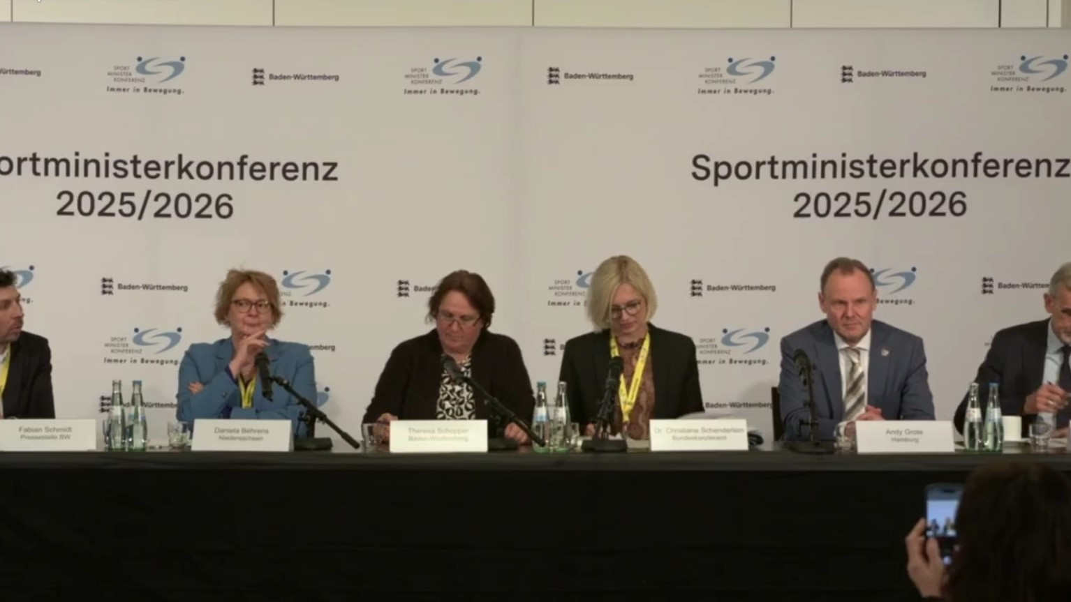 Die Teilnehmenden der Pressekonferenz bei der 53. Sportministerkonferenz auf Norderney sitzen nebenaneinder auf dem Podium.