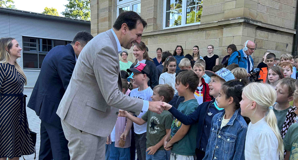 Kultusminister Jung mit Grundschulkinder. Der Minister schüttelt einem Jungen die Hand.
