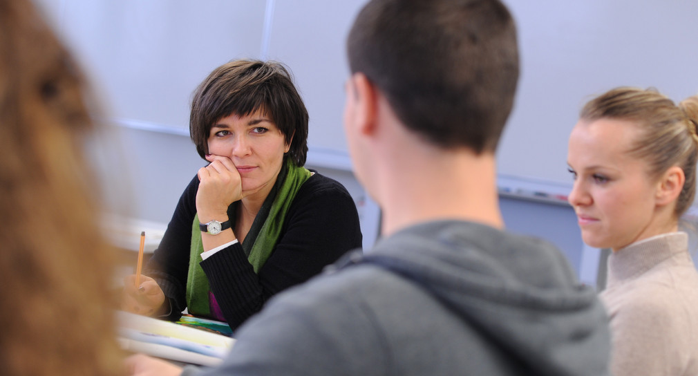 Dozentin mit einer gemischten Gruppe von jungen Menschen im Klassenraum