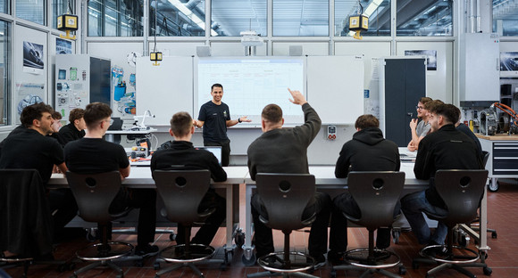 Schüler und ein Lehrer im Unterricht in einem Werkstattgebäude