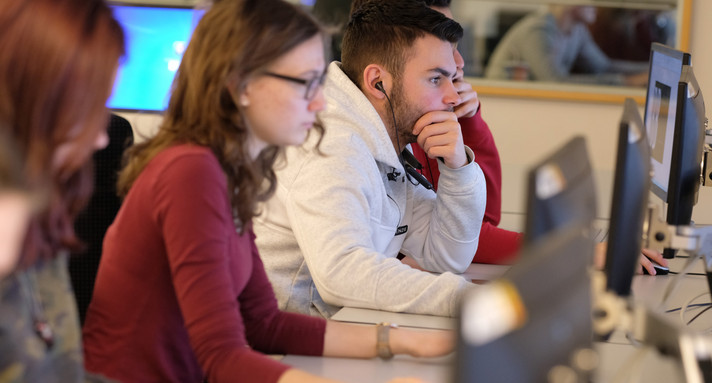 Mehrere Jugendliche schauen konzentriert auf ihren Monitor
