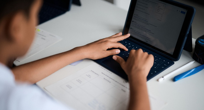 SChüler sitzt vor Notebook und tippt etwas.