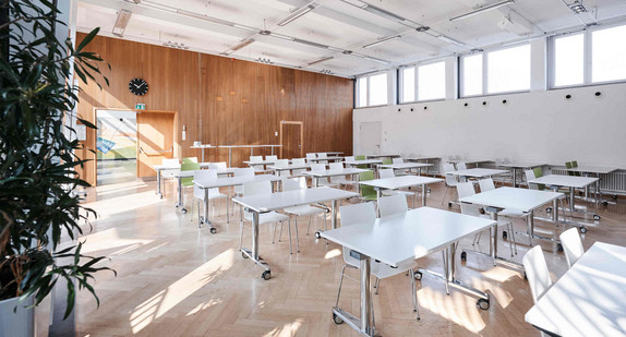 Ein sonnendurchfluteter Schulraum mit Tischen und Stühlen