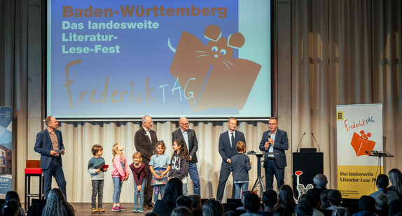 Foto der Veranstaltung mit Beteiligten auf der Bühne. 