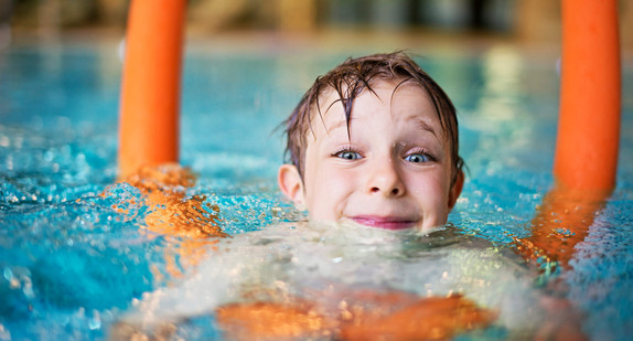 Ein Junge mit einer Schwimmnudel in einem Schwimmbecken