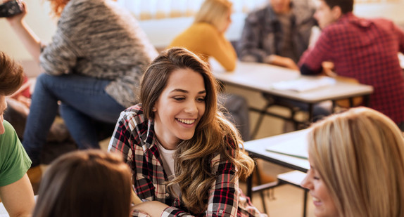 Lächelnde Schülerinnen und Schüler genießen die Pause im Klassenraum und kommunizieren.
