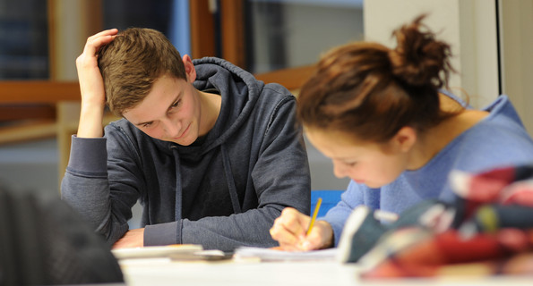 Eine Schülerin und ein Schüler sind konzentriert am Arbeitsplatz am Lernen