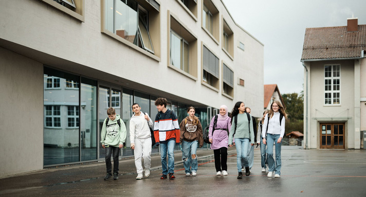 Eine Gruppe Schülerinnen und Schüler laufen vor dem Gebäude