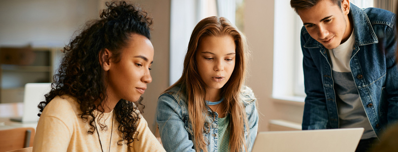 Gruppe von Schülerinnen und Schüler im Teenageralter im Klassenraum vor einem Monitor am diskutieren